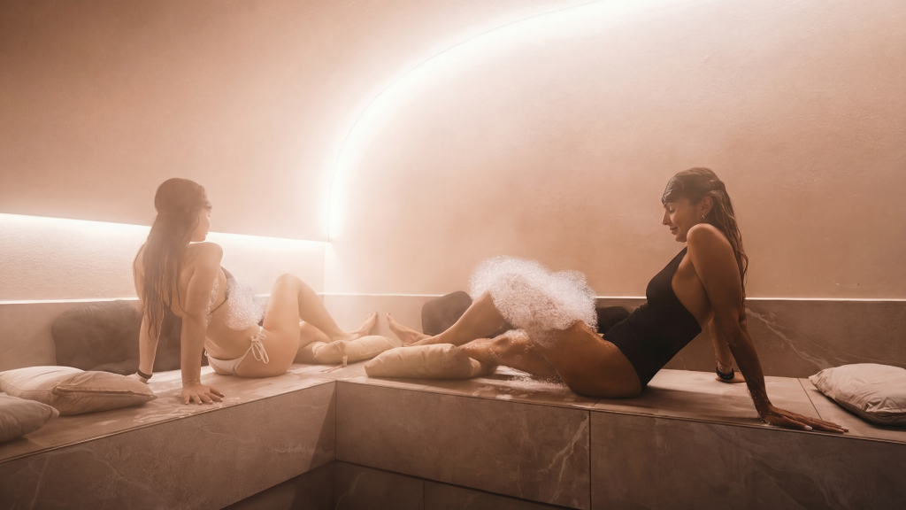 Interior de hammam tradicional donde dos personas disfrutan de una experiencia de vapor y relajación.